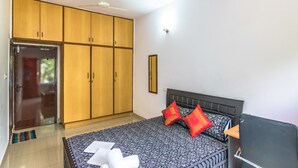 A bedroom with a bed, a wardrobe, and a ceiling fan. - Luxury Apartment in Indiranagar (Bengaluru)