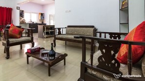 A living room with two sofas, a coffee table with a bottle and glasses, and a bookshelf. - Luxury Apartment in Indiranagar (Bengaluru)