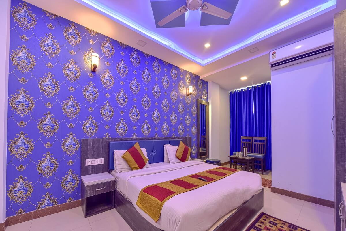 A hotel room with a large bed, a nightstand, a desk, and a chair.