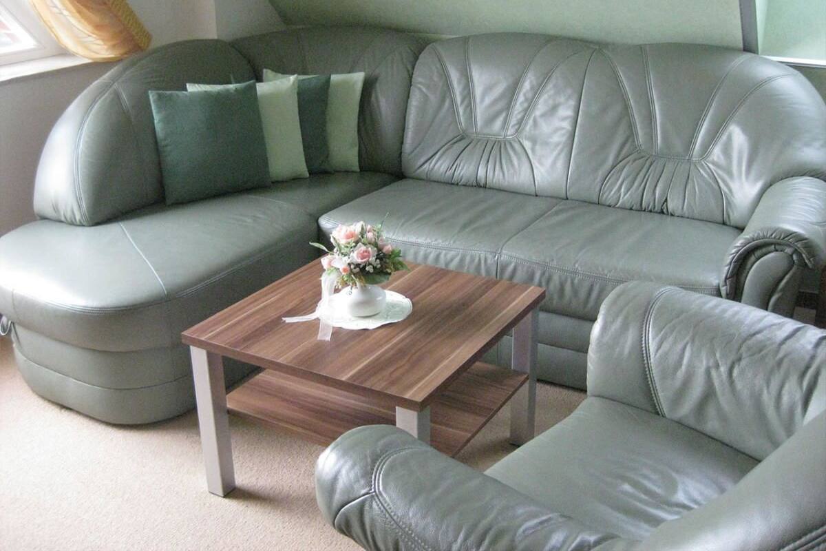 A grey leather sofa with a wooden coffee table and a cushion.