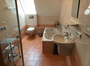 A bathroom with a toilet, bathtub, and two sinks. - Haus Schwielochsee (Schwielochsee)