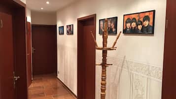 Ein Korridor mit Holztüren, einem Holzstuhl und gerahmten Bildern an der Wand.