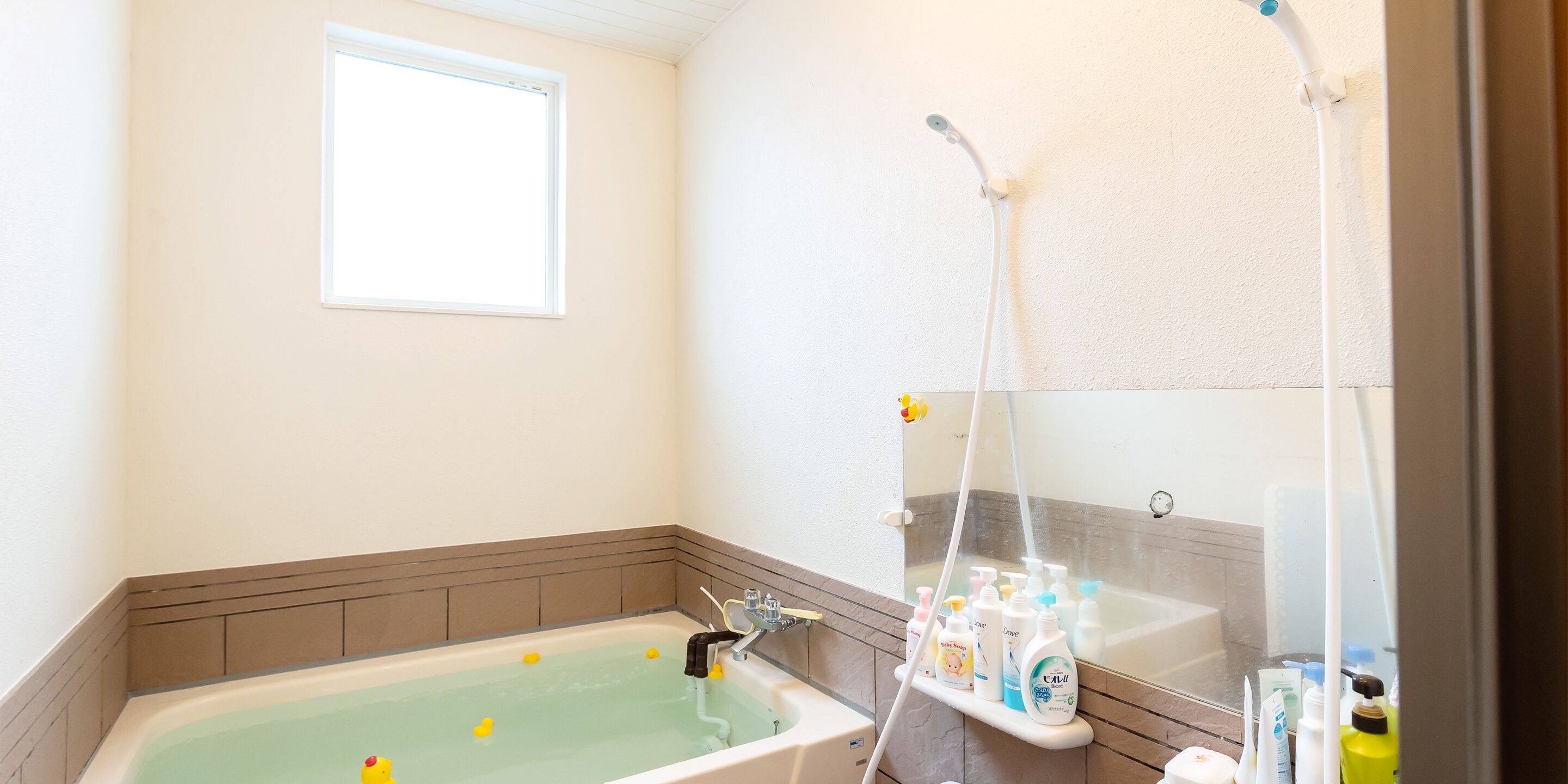 A bathroom with a bathtub, a window, and a shower area with toiletries.