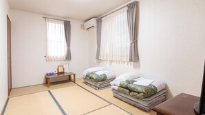 A hotel room with two beds, a TV, a small table, and an air conditioning unit. - Pension Setsurin (Sapporo)