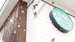 A sign with Japanese characters, a wooden wall, and electrical wires. - Pension Setsurin (Sapporo)