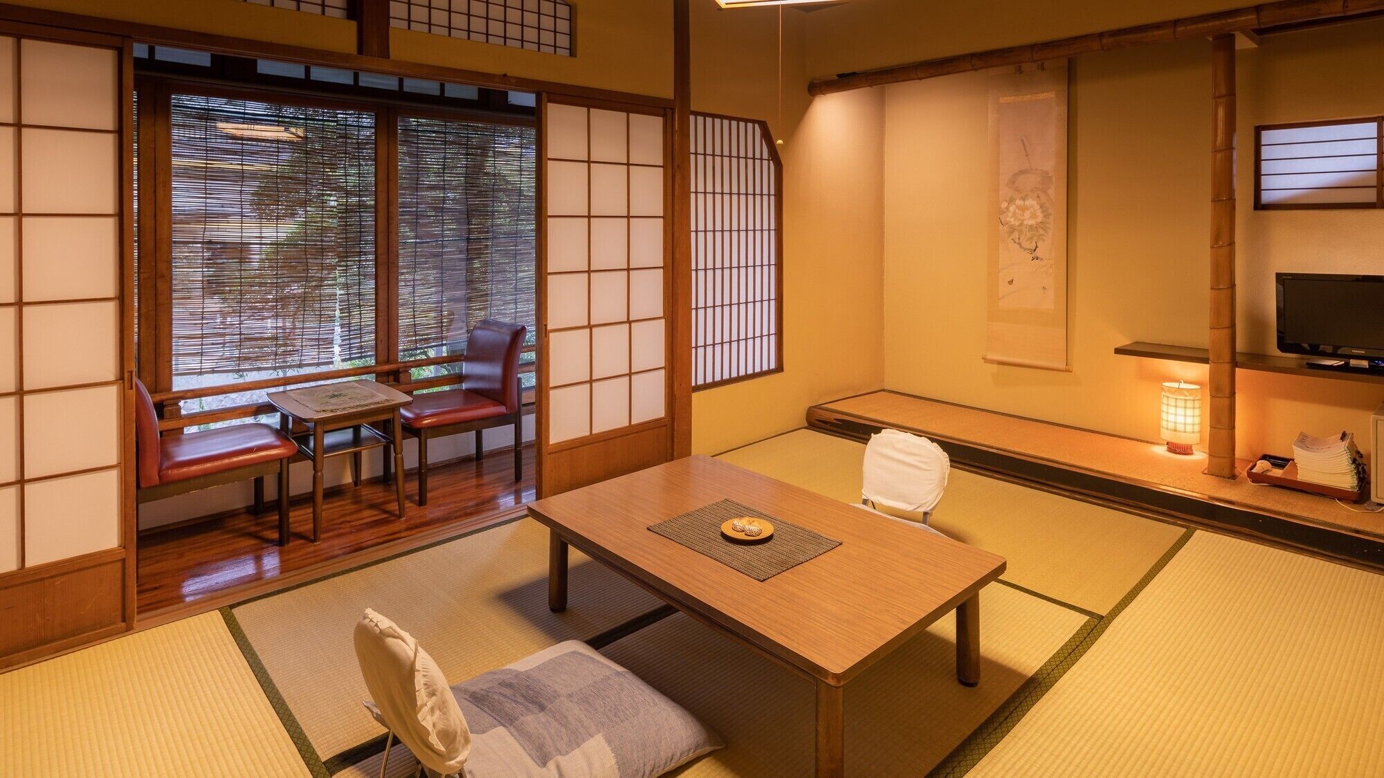 A traditional Japanese room with tatami flooring, a low table, a sofa, and sliding doors.