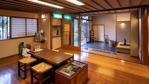 A traditional Japanese room with tatami flooring, a wooden table, and a sliding door leading to a garden.
