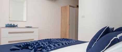 Un dormitorio con cama, cómoda, televisor y armario.