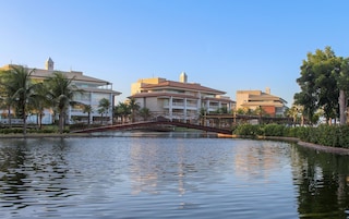 Um hotel com uma ponte sobre águas calmas, cercado por palmeiras e vegetação.