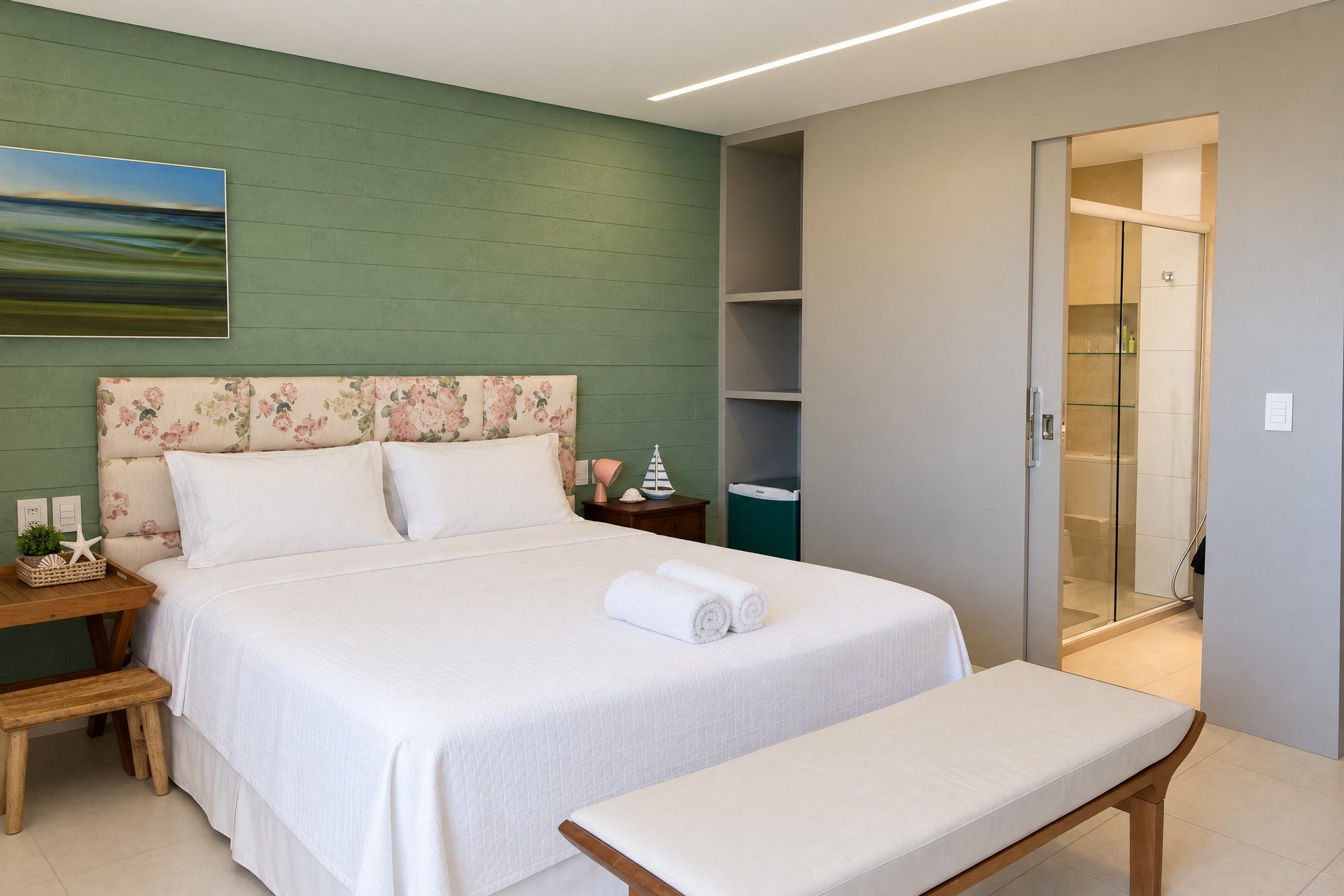 Une chambre à coucher bien aménagée, avec un lit, des tables de chevet, un banc et une cabine de douche en verre.
