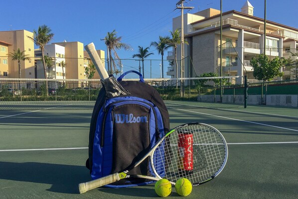 A tennis court with a Wilson-branded bag, tennis racket, and balls. - Penthouse Apartment with Hot Tub near Beach (Aquiraz)