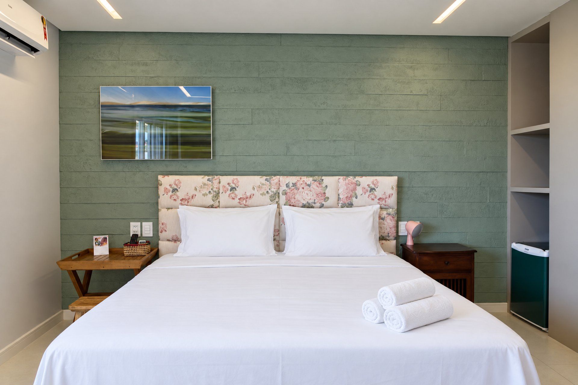 Una habitación de hotel con una cama, una mesita de noche, un cuadro colgado en la pared y un armario.