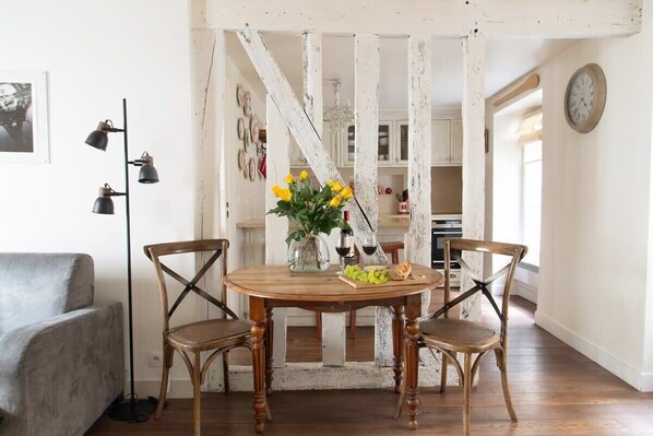 A dining area with a wooden table, two chairs, and a vase with yellow flowers.