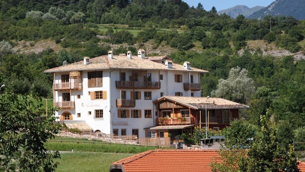 A multi-story hotel with balconies, surrounded by lush greenery and mountains. - Relais Vecchio Maso (Trento)