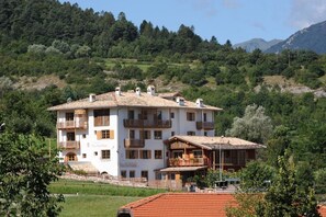 A multi-story hotel with balconies, surrounded by lush greenery and mountains. - Relais Vecchio Maso (Trento)