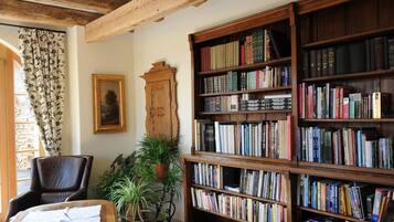 A cozy room with a large wooden bookshelf filled with books, a leather armchair, and a wooden coffee table.