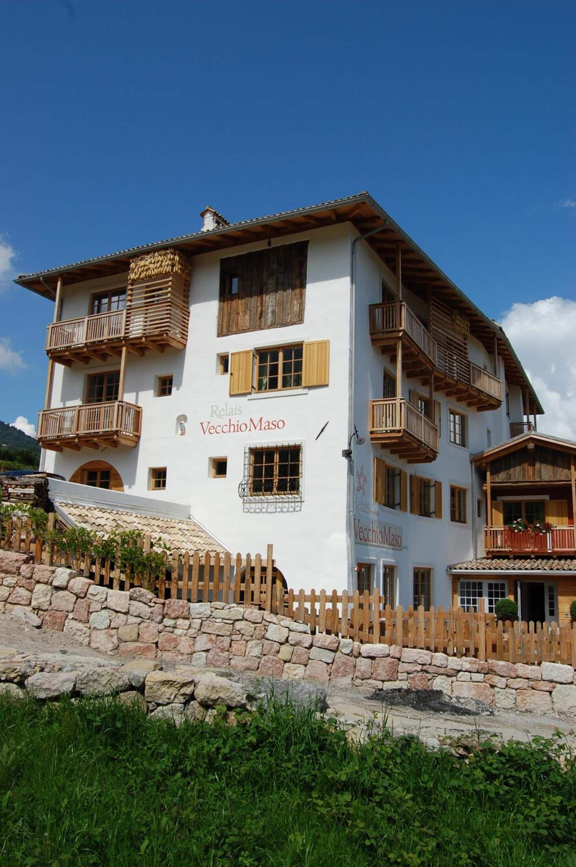 Un hotel de varios pisos con balcones de madera y una pared de piedra al frente.
