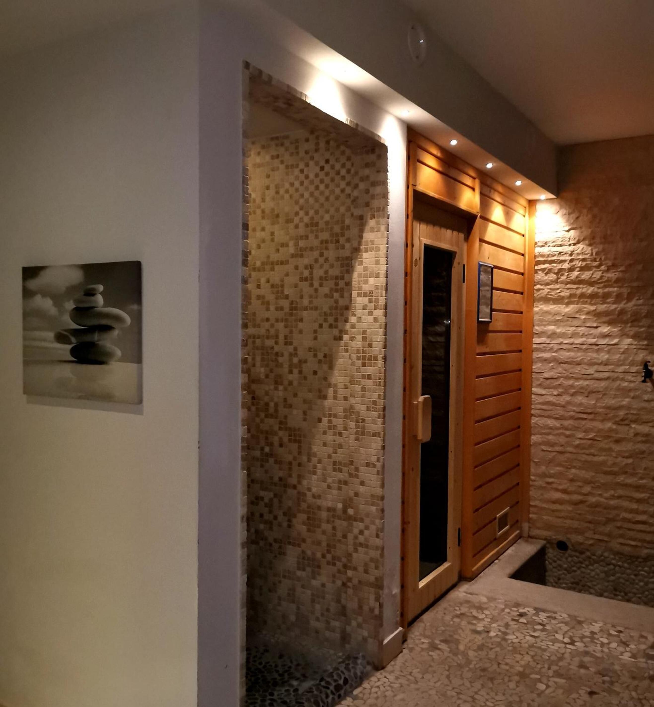 A spa entrance with a mosaic wall, wooden door, and a stone pathway.