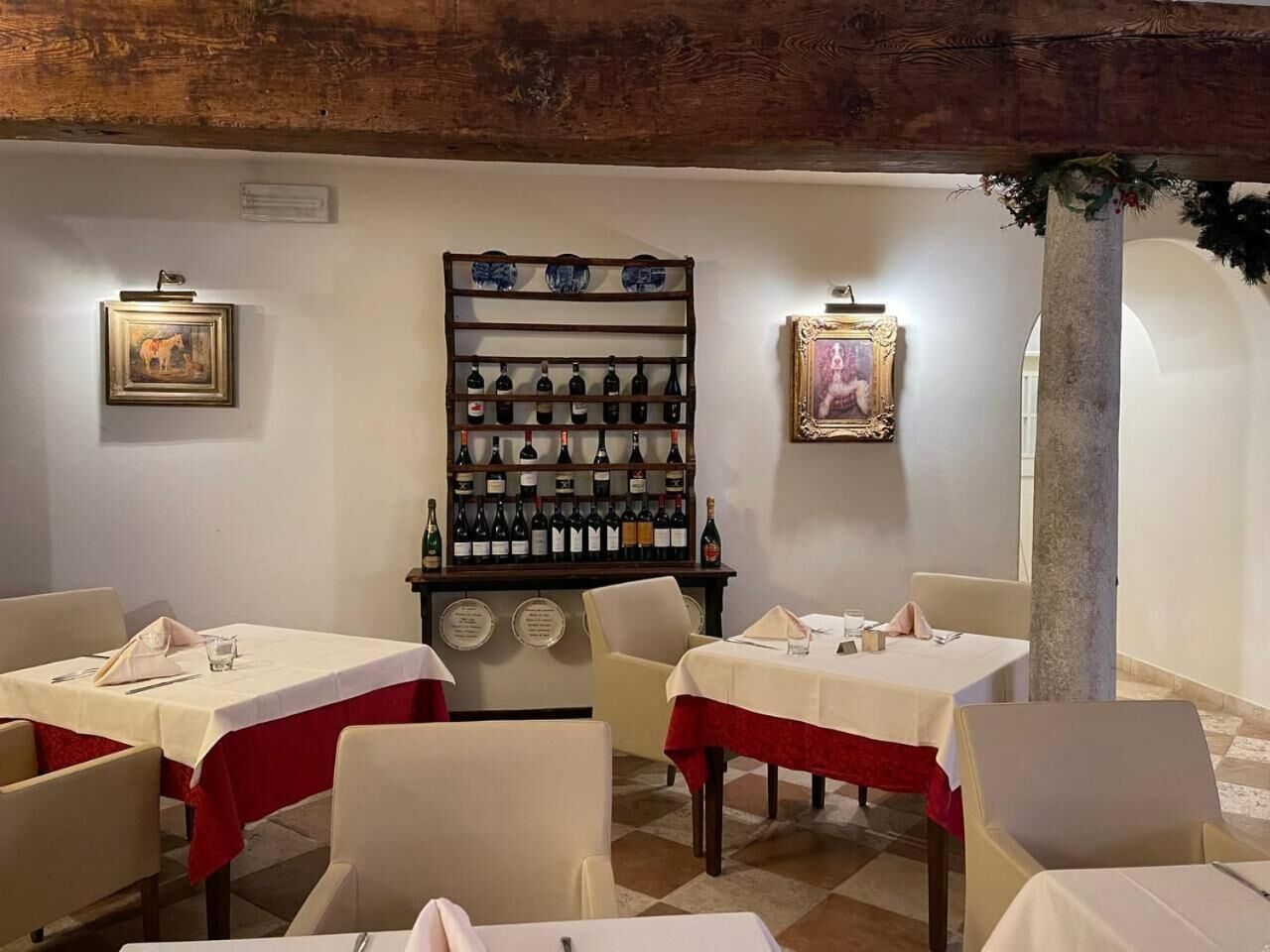 Un restaurant avec des tables dressées, un présentoir à bouteilles et des œuvres d’art encadrées accrochées aux murs.