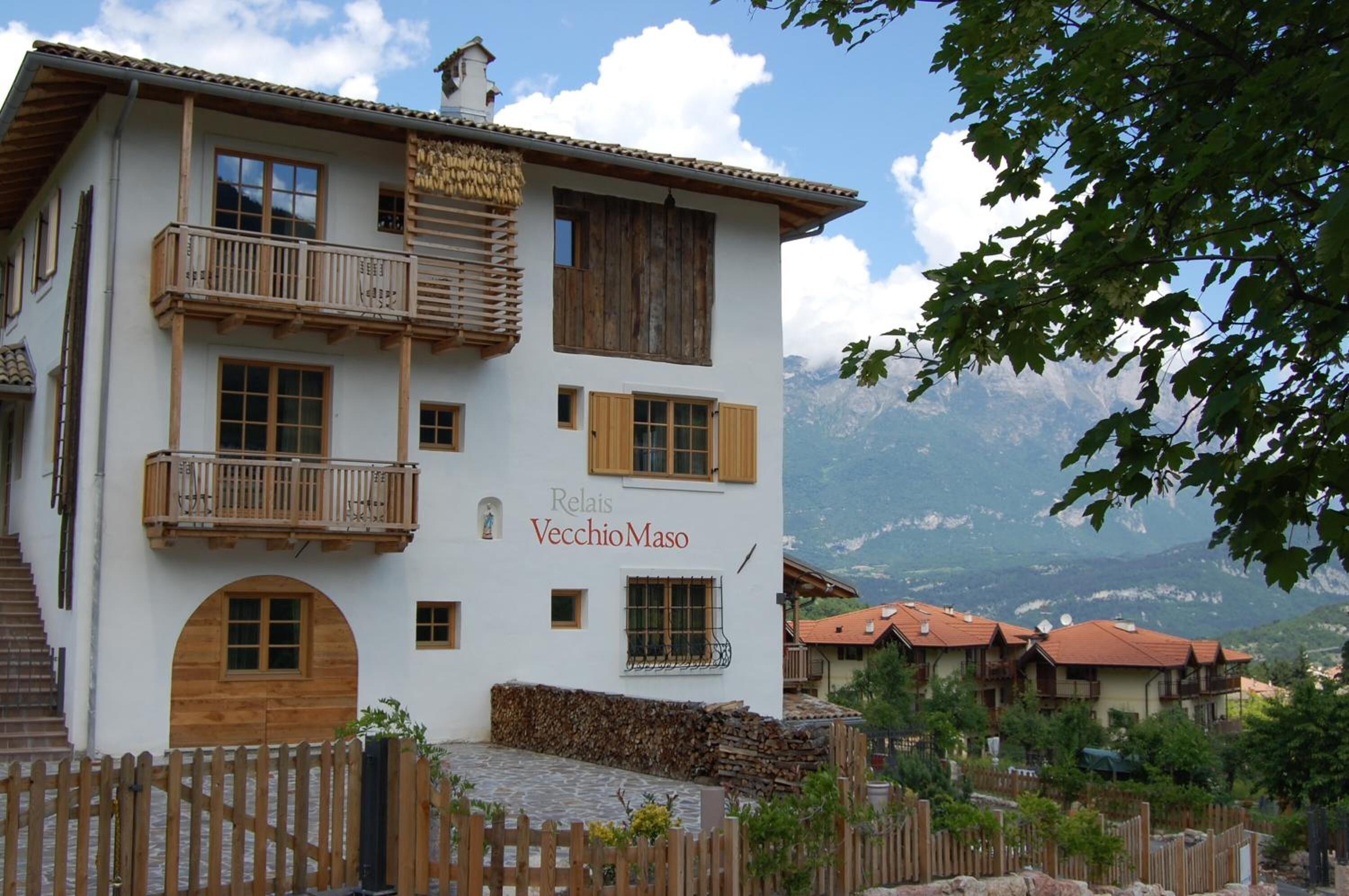 A two-story building with wooden balconies and a sign reading "Relais VecchioMaso."