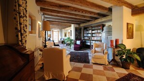 A cozy living room with wooden beams, a checkered floor, and a bookshelf filled with books. - Relais Vecchio Maso (Trento)