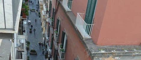 A narrow street flanked by multi-story buildings with balconies, some with plants.