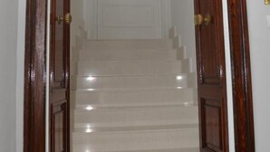 Una escalera conduce a una habitación con una puerta blanca y un panel de vidrio decorativo.