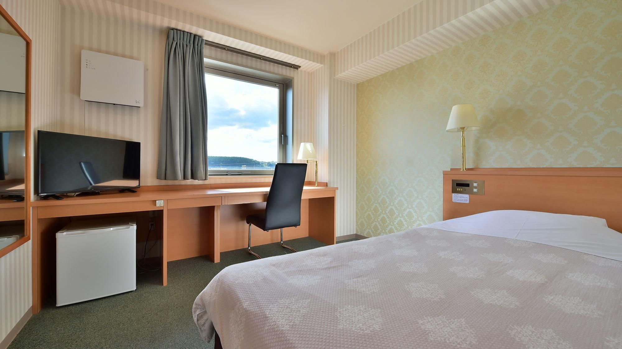 A hotel room with a bed, desk, chair, television, and a window with curtains.