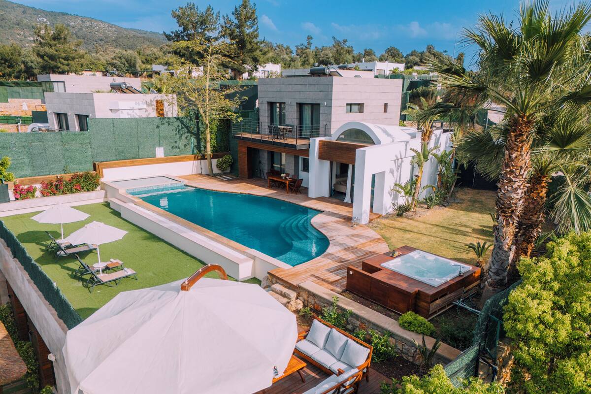 Un área de piscina moderna con piscina rectangular, sillas de descanso y un jacuzzi.