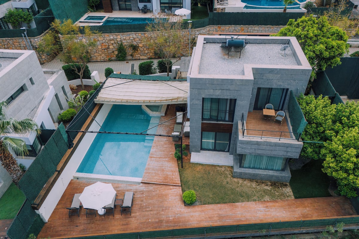 Un moderno complejo residencial con piscina, mobiliario exterior y un muro de piedra.