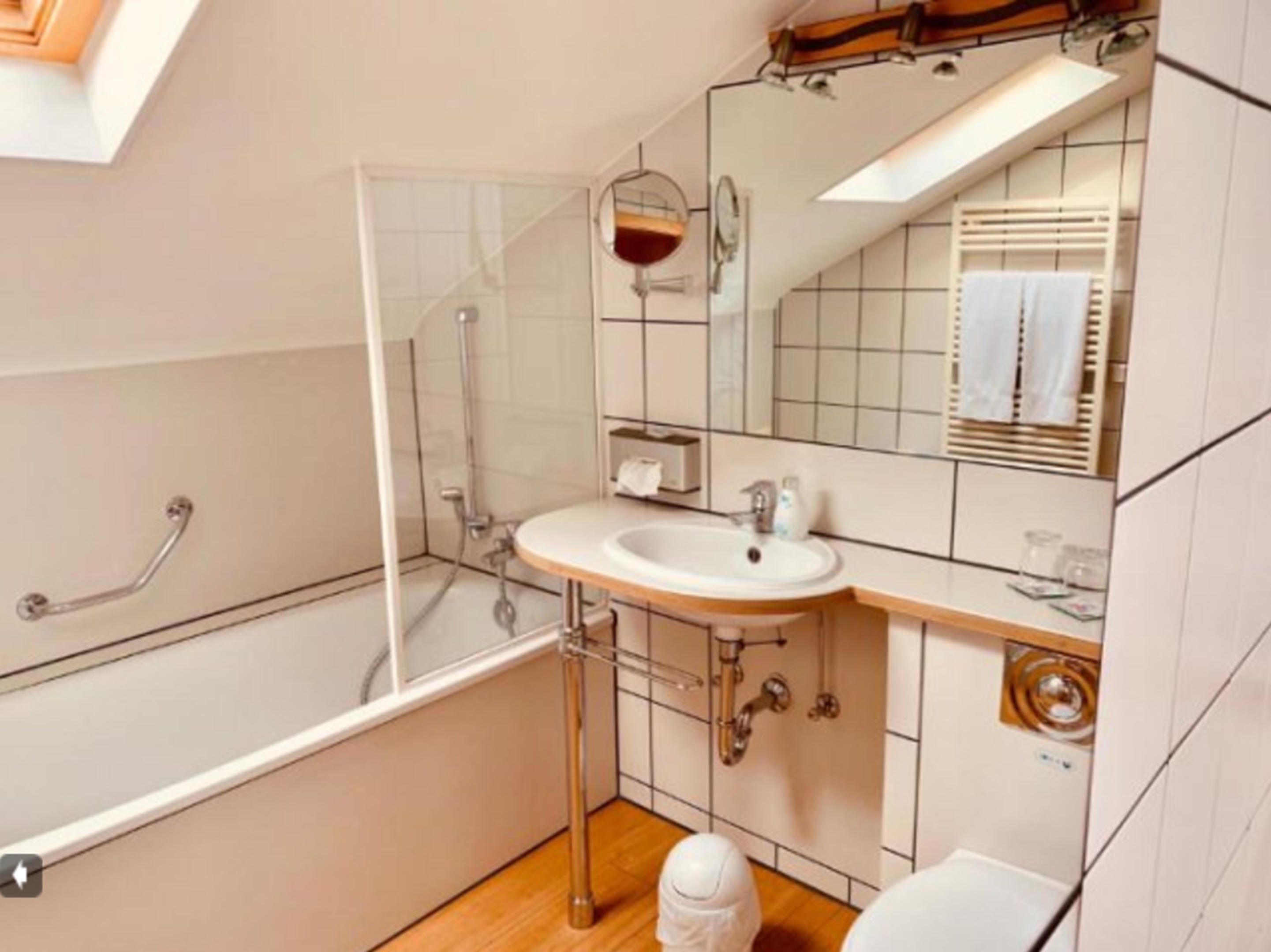 A modern bathroom with a glass-enclosed shower, a white sink with a mirror above, and a toilet.