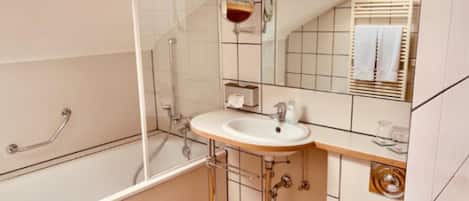Un baño moderno con ducha de vidrio, un lavamanos blanco con espejo superior y un inodoro.