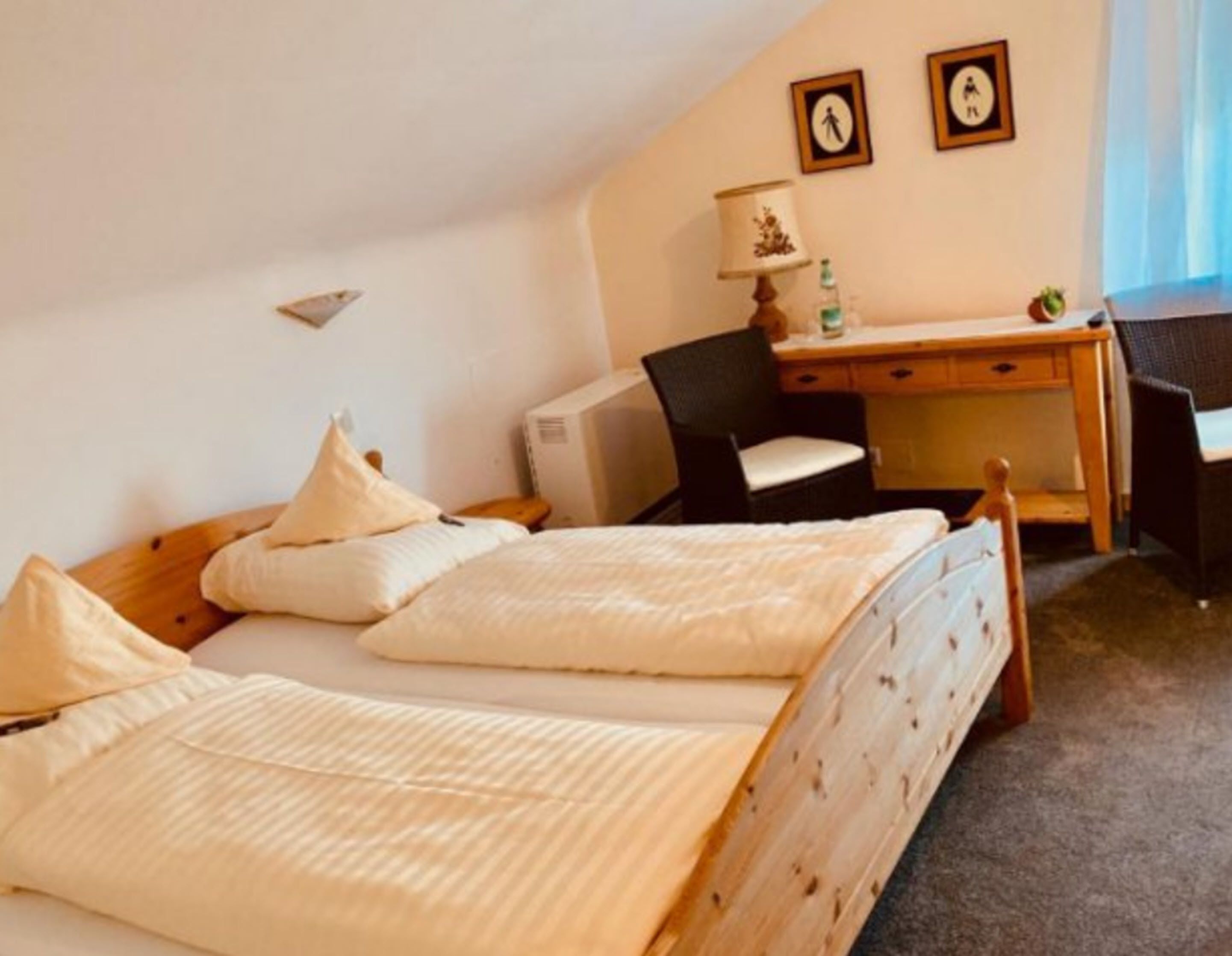 A bedroom with two beds, a desk, a chair, and a small table with a lamp.