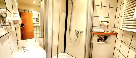 A modern bathroom with a glass-enclosed shower, a white sink, and a toilet.