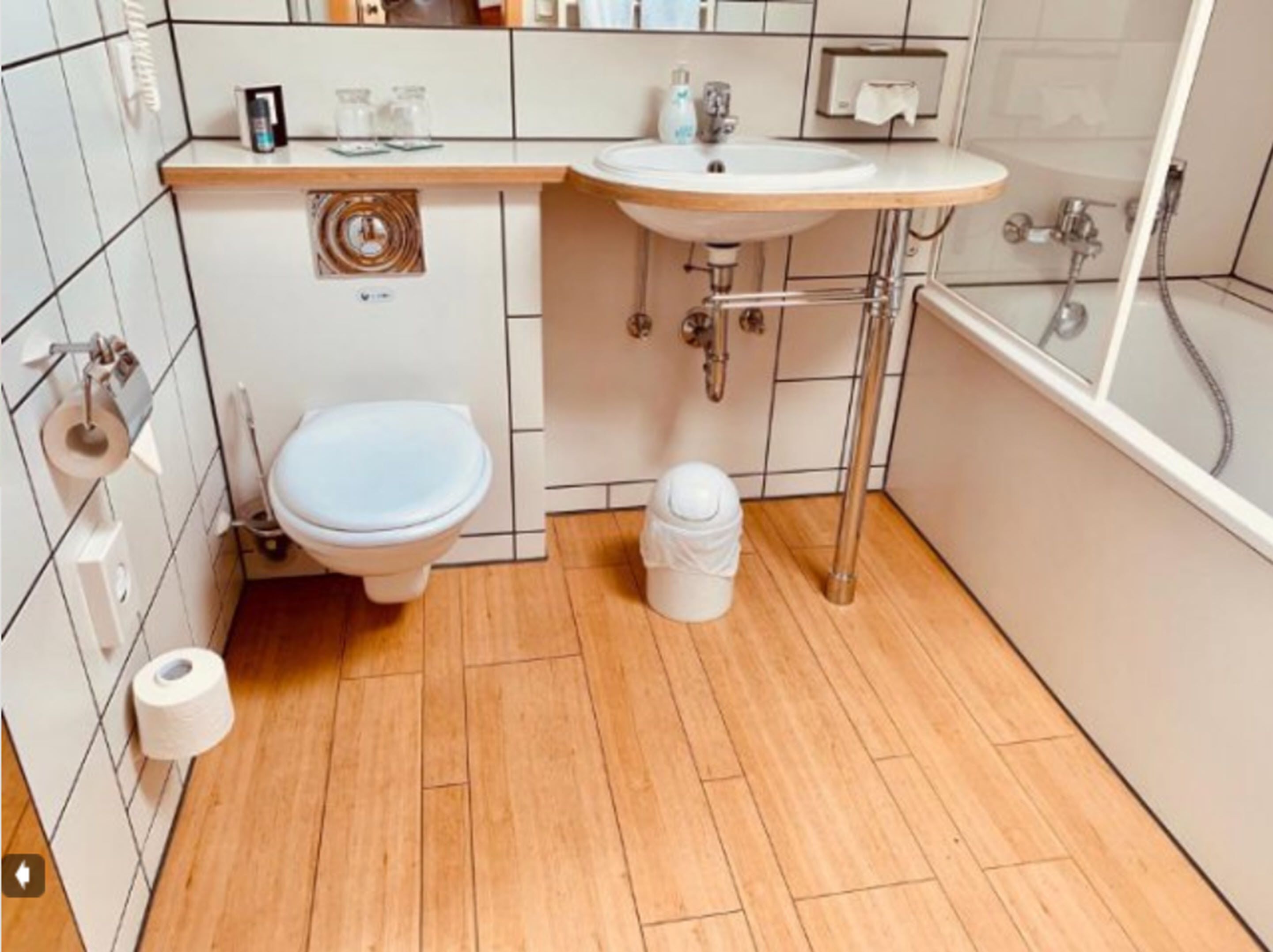 A small bathroom with a toilet, sink, and shower.