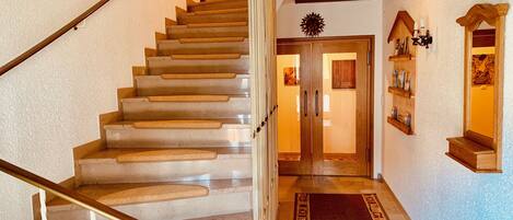 Un escalier avec une rampe en bois menant à une porte dotée de panneaux de verre.
