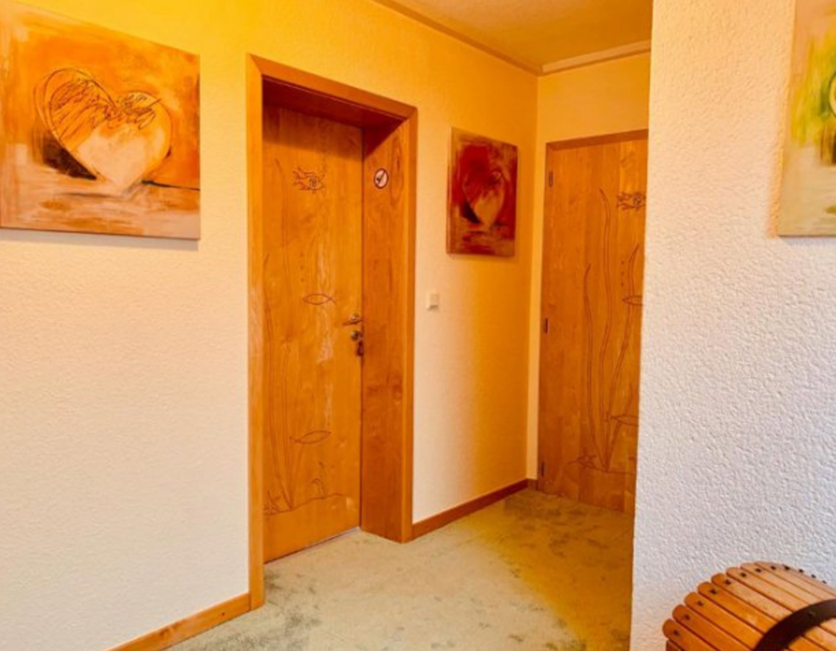 Ein Flur mit Holztüren, einem Herzbild und einer kleinen Mülltonne.