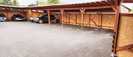 Un área de estacionamiento techada con varios coches aparcados bajo una estructura de madera.