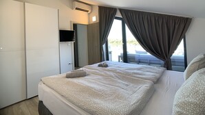 Ein modernes Hotelzimmer mit einem großen Bett, einem an der Wand montierten Fernseher und Blick ins Freie.