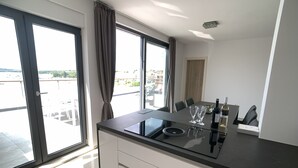 Eine moderne Küche mit schwarzer Arbeitsplatte, weißen Schränken und einem Essbereich mit Tisch und Stühlen.