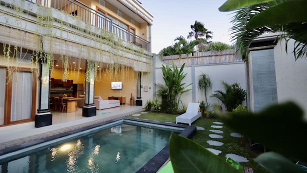 A modern building with a pool, outdoor seating, and greenery. - Kubu Willis (Legian)