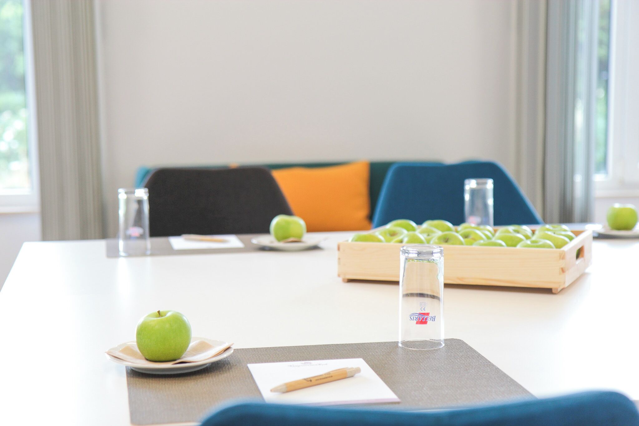 A conference table with a glass of water, a plate with an apple, and a notebook.