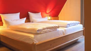 A bedroom with a wooden bed, white bedding, and a red accent wall.
