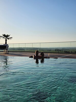 Una piscina techada, una piscina al aire libre, sombrillas