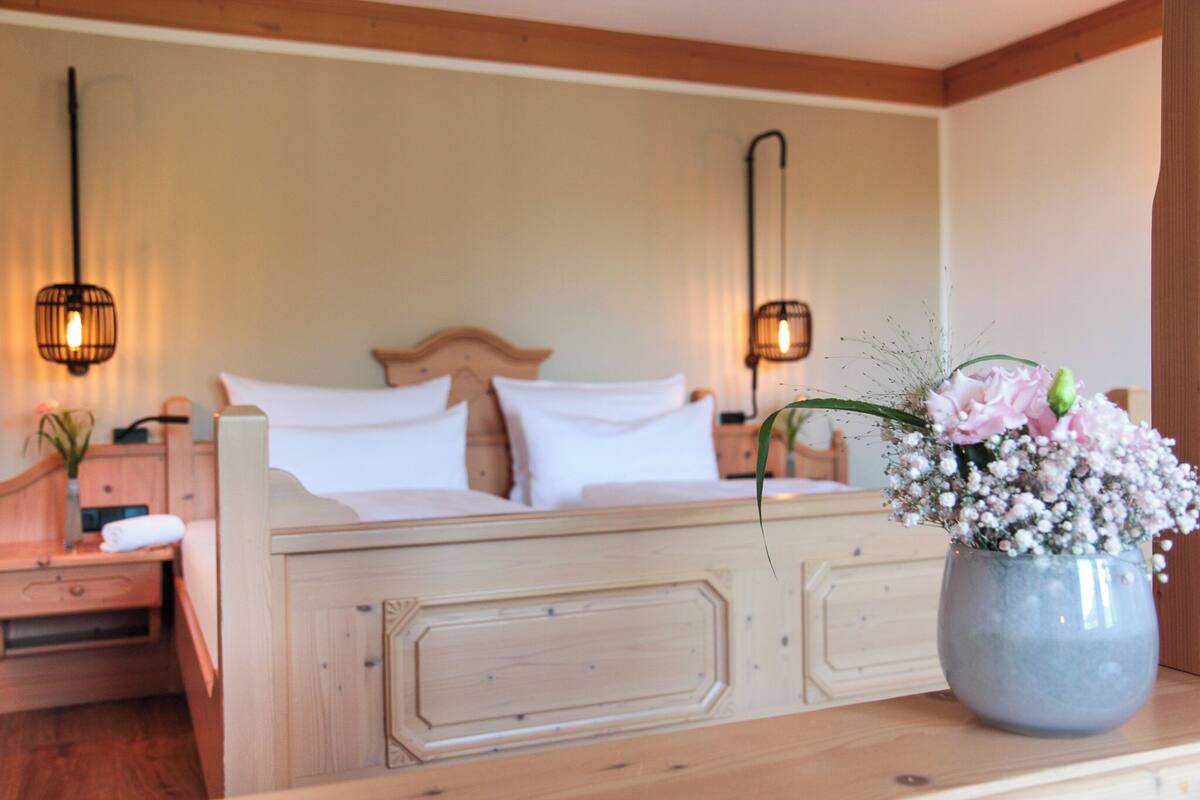 A bedroom with a wooden bed, bedside tables, and a vase with flowers.