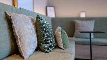 Un canapé vert avec trois coussins de textures et de couleurs différentes.