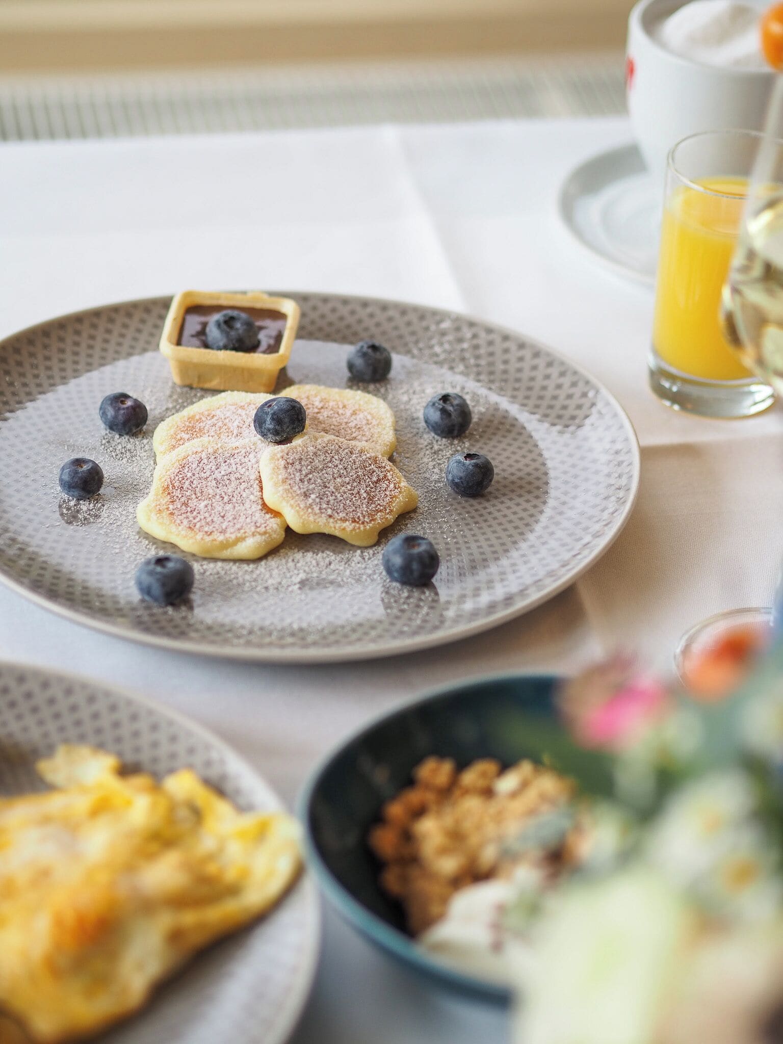 En frukostuppläggning med pannkakor, blåbär och en liten skål med sylt på en tallrik.