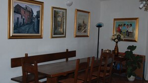 A dining area with a wooden table and chairs, framed paintings on the wall, and a vase with flowers on a side table. - Isolated villa surrounded by greenery a stone's throw from Olbia (Olbia)