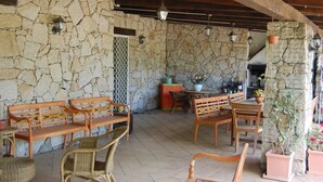 A stone-walled patio with wooden furniture, including benches and chairs, and hanging lanterns. - Isolated villa surrounded by greenery a stone's throw from Olbia (Olbia)