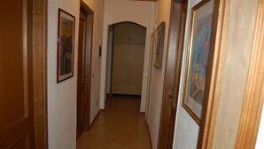 A hallway with wooden doors, framed artwork on the walls, and a tiled floor. - Isolated villa surrounded by greenery a stone's throw from Olbia (Olbia)